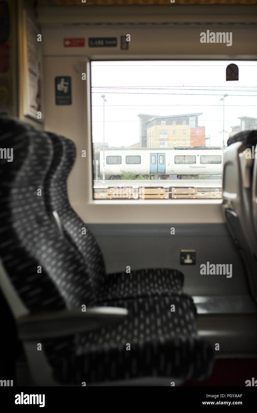 Two empty airline style seats on an Abellio Greater Anglia train,while on a platform Stock Photo