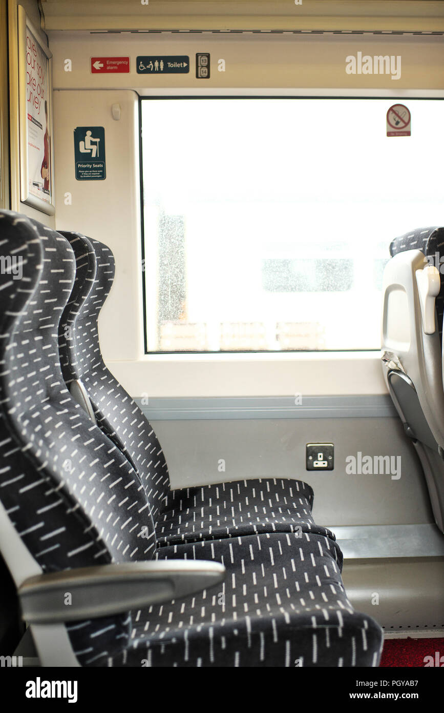Two empty airline style seats on an Abellio Greater Anglia train,while on a platform Stock Photo