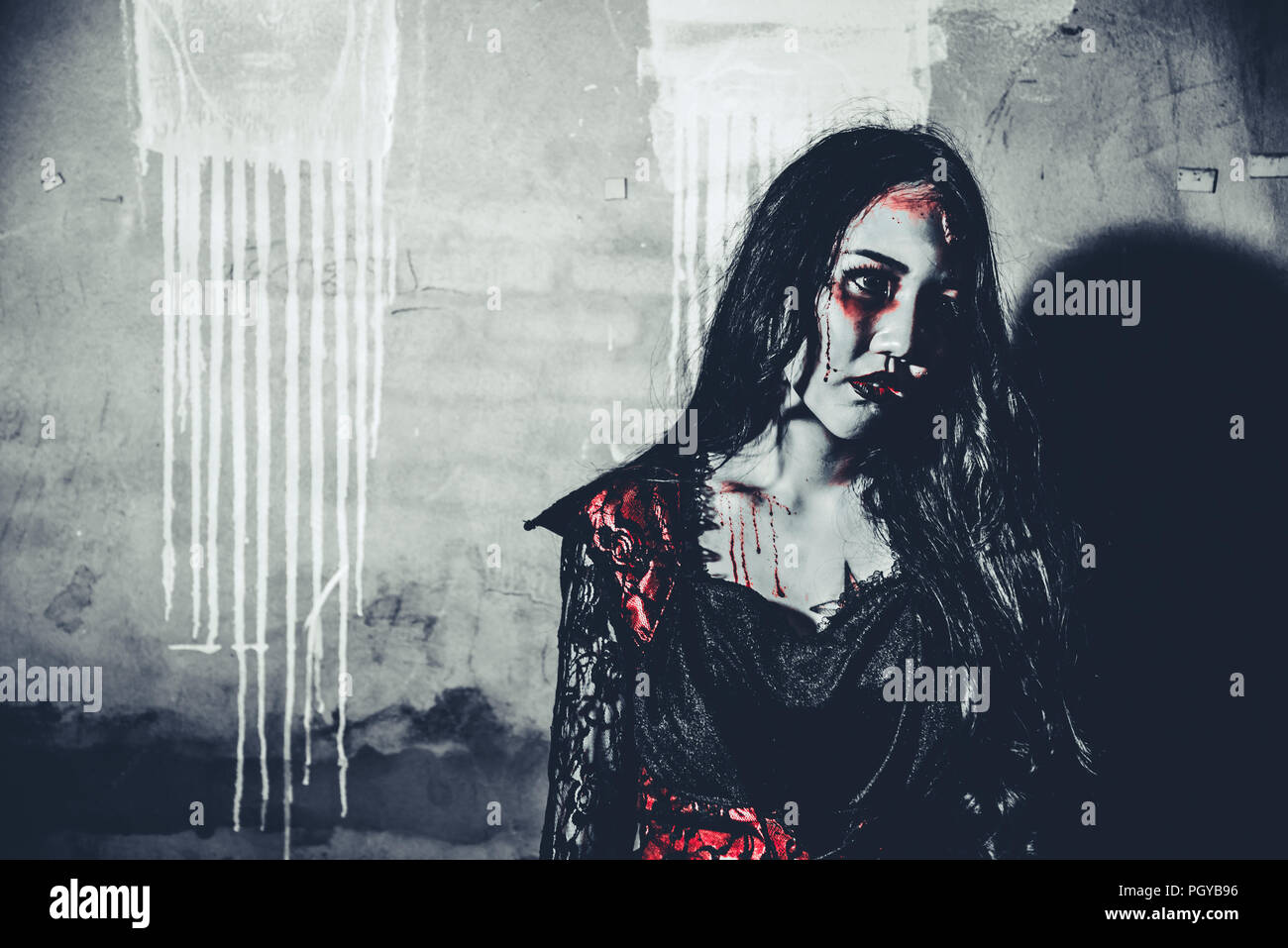 Female zombie corpse standing in front of grunge wall in abandoned house. Horror and Ghost concept. Halloween day festival and scary movie theme. Haun Stock Photo