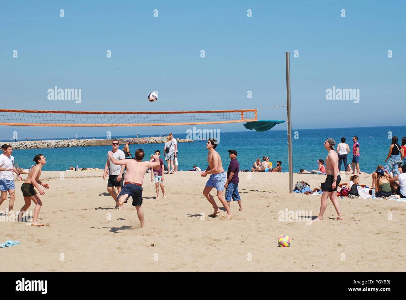 Men playing volleyball on the beach at Barcelona in Catalonia, Spain on April 17, 2018. Stock Photo