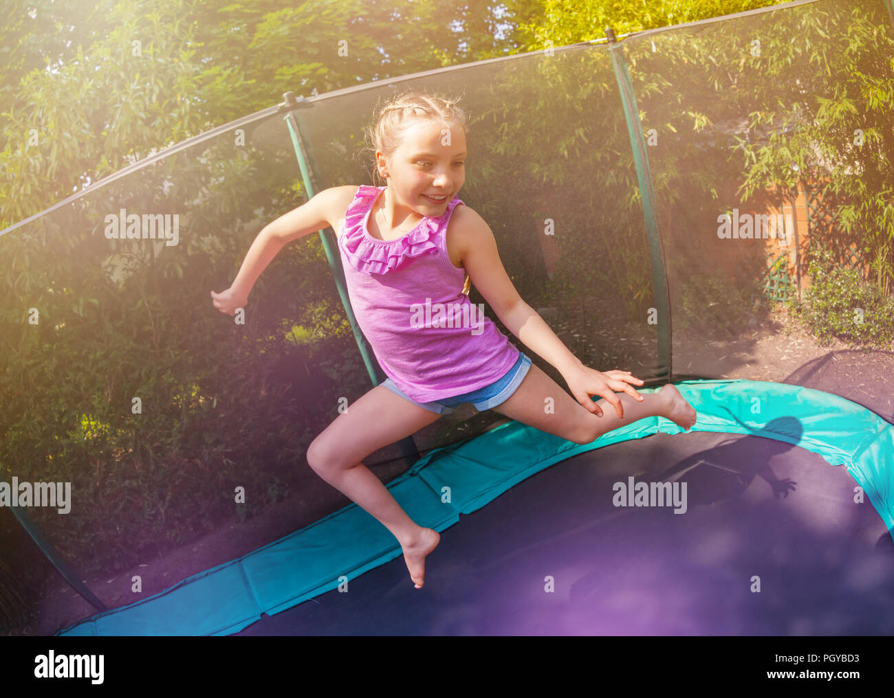 Close-up portrait of preteen girl having fun jumping on the backyard ...