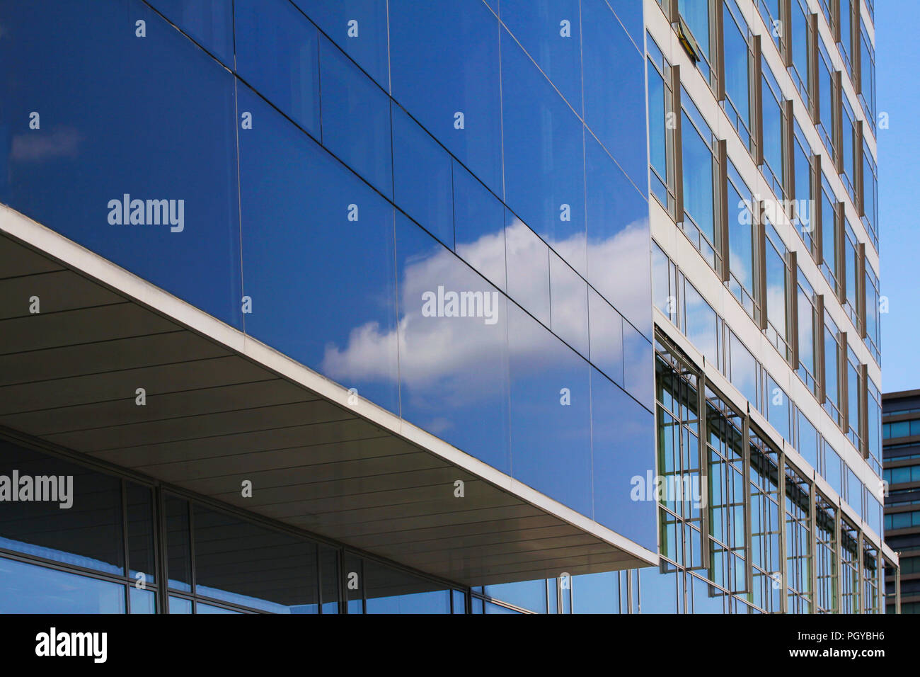 Modern corporate highrise building with glass facade reflecting sky ...