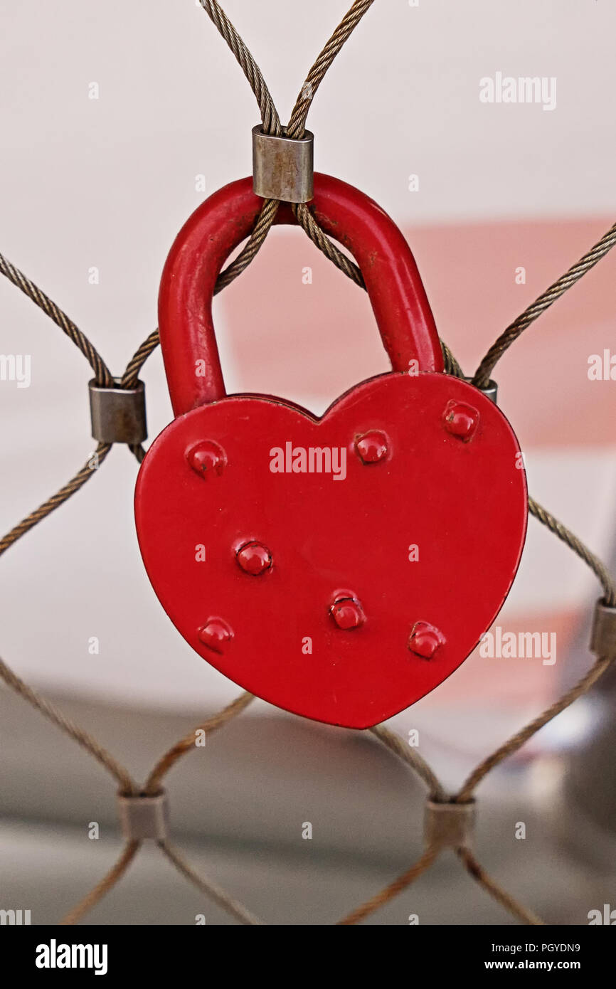 Close up view of red heart shape padlock hanging on fence. Concept of ...