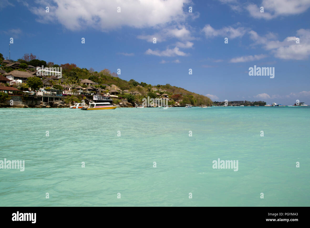 The beach of Lembongan, next to the indonesian Bali. The water has a beautiful turquoise blue color through the reflection of the sun on the white san Stock Photo