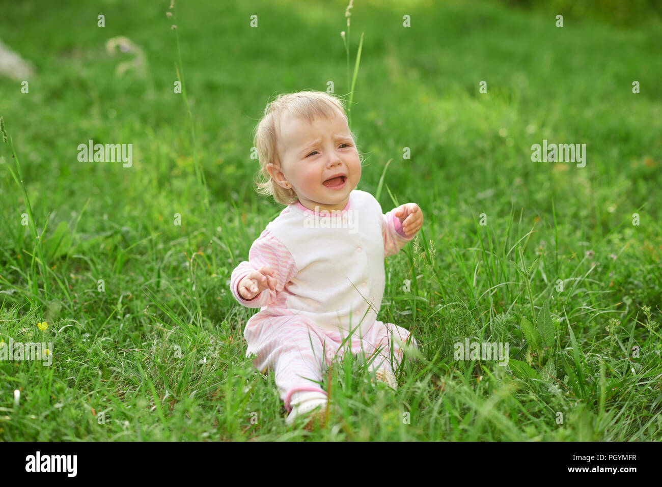 Crying Little Girl Sitting On Green Grass Looking For Mom