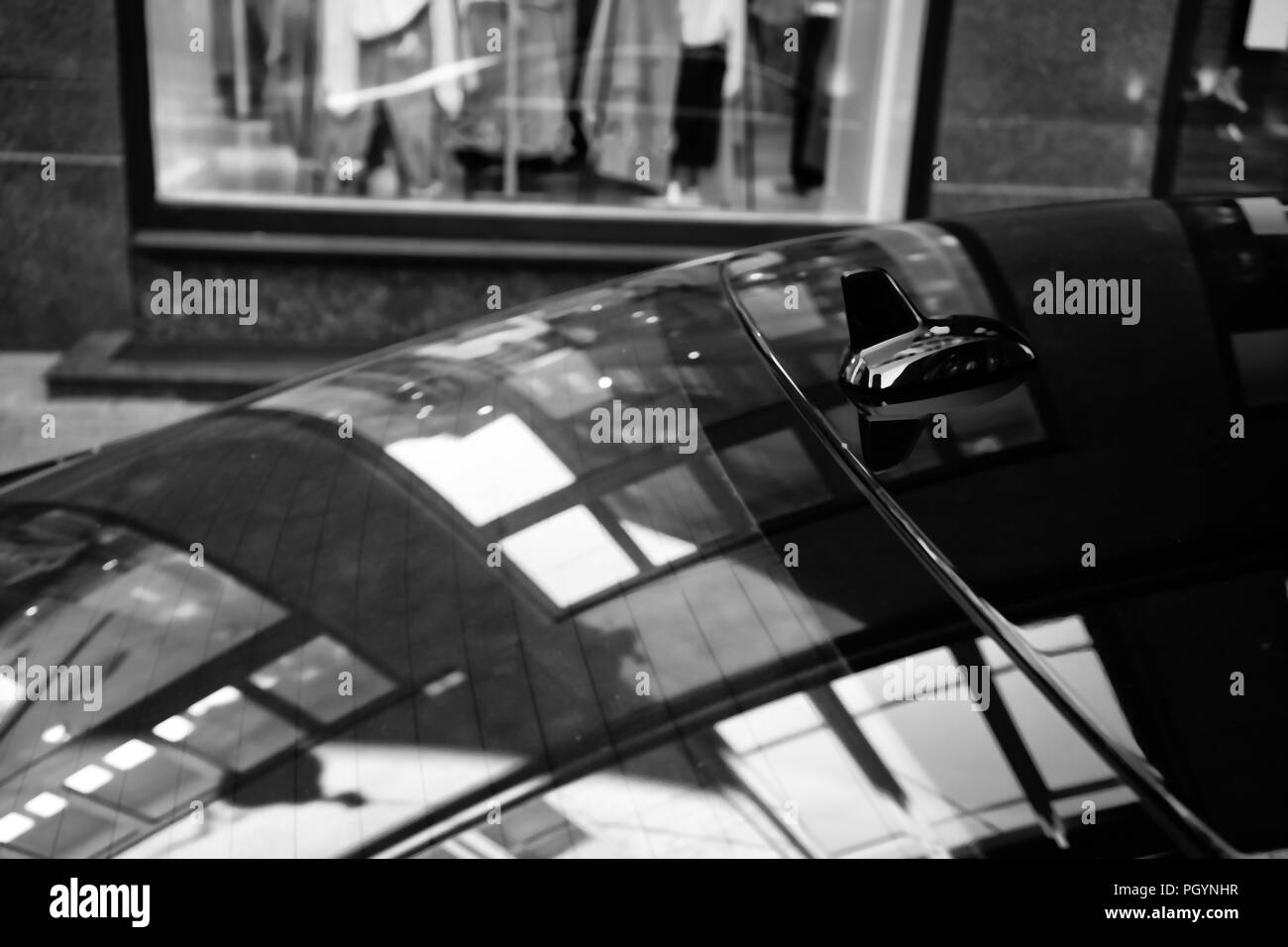 Reflection of the lines and shapes of the shop window on the glass and roof of the car. Black and white stylization Stock Photo