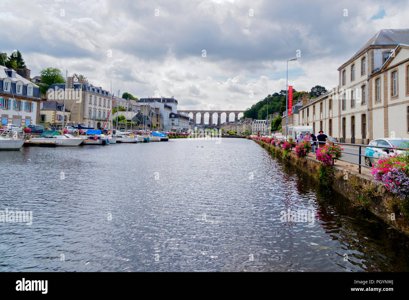 Morlaix, France - August 10 2018: Up the Dossen River, towards Morlaix Viaduct. boats moored on the left, buildings on both banks. A small group of to Stock Photo