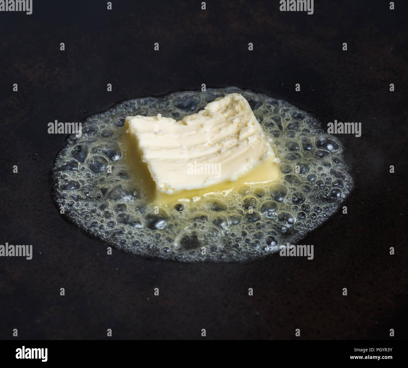 A pat of butter melts in a hot carbon steel pan Stock Photo