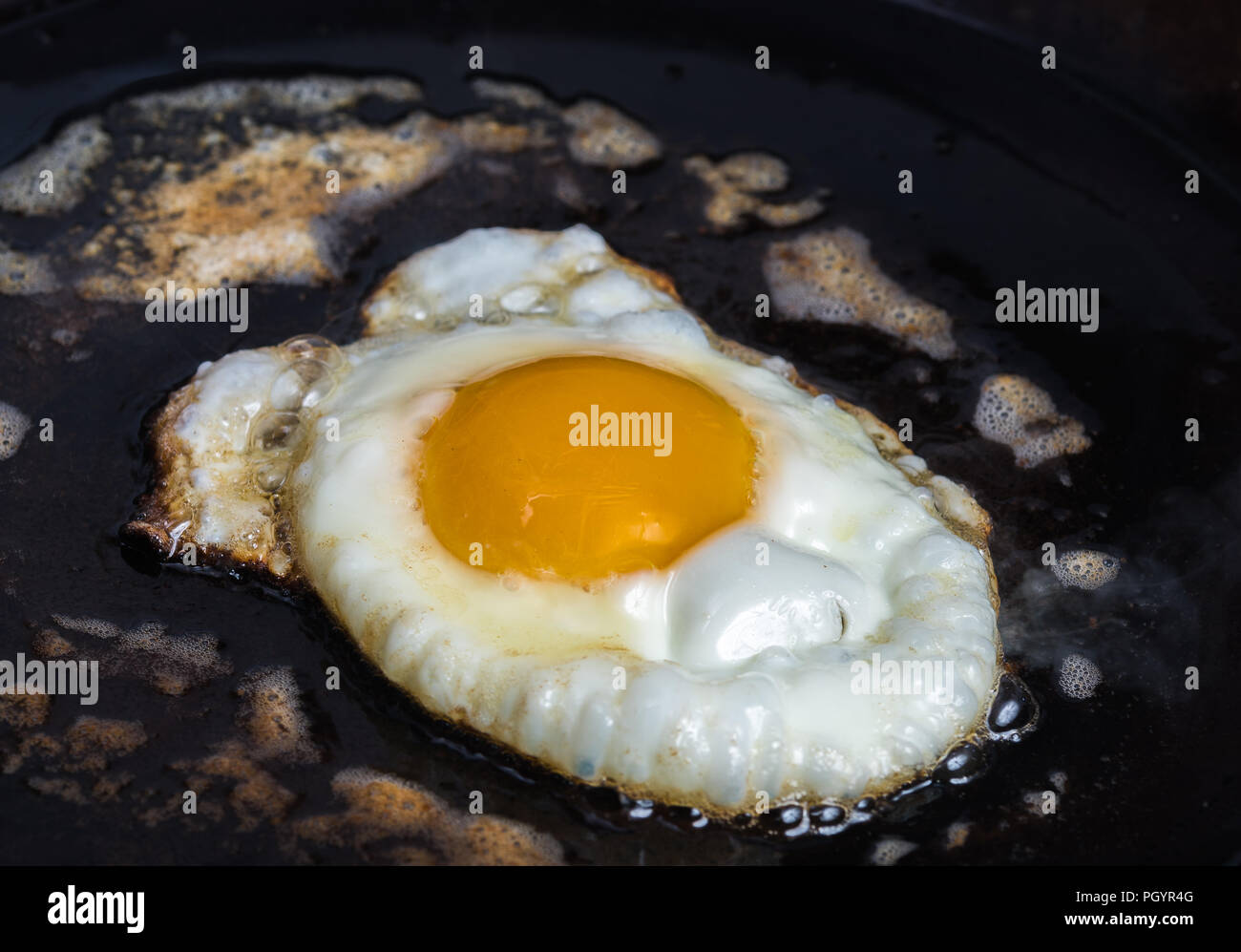 An egg fries in butter in a carbon steel pan Stock Photo