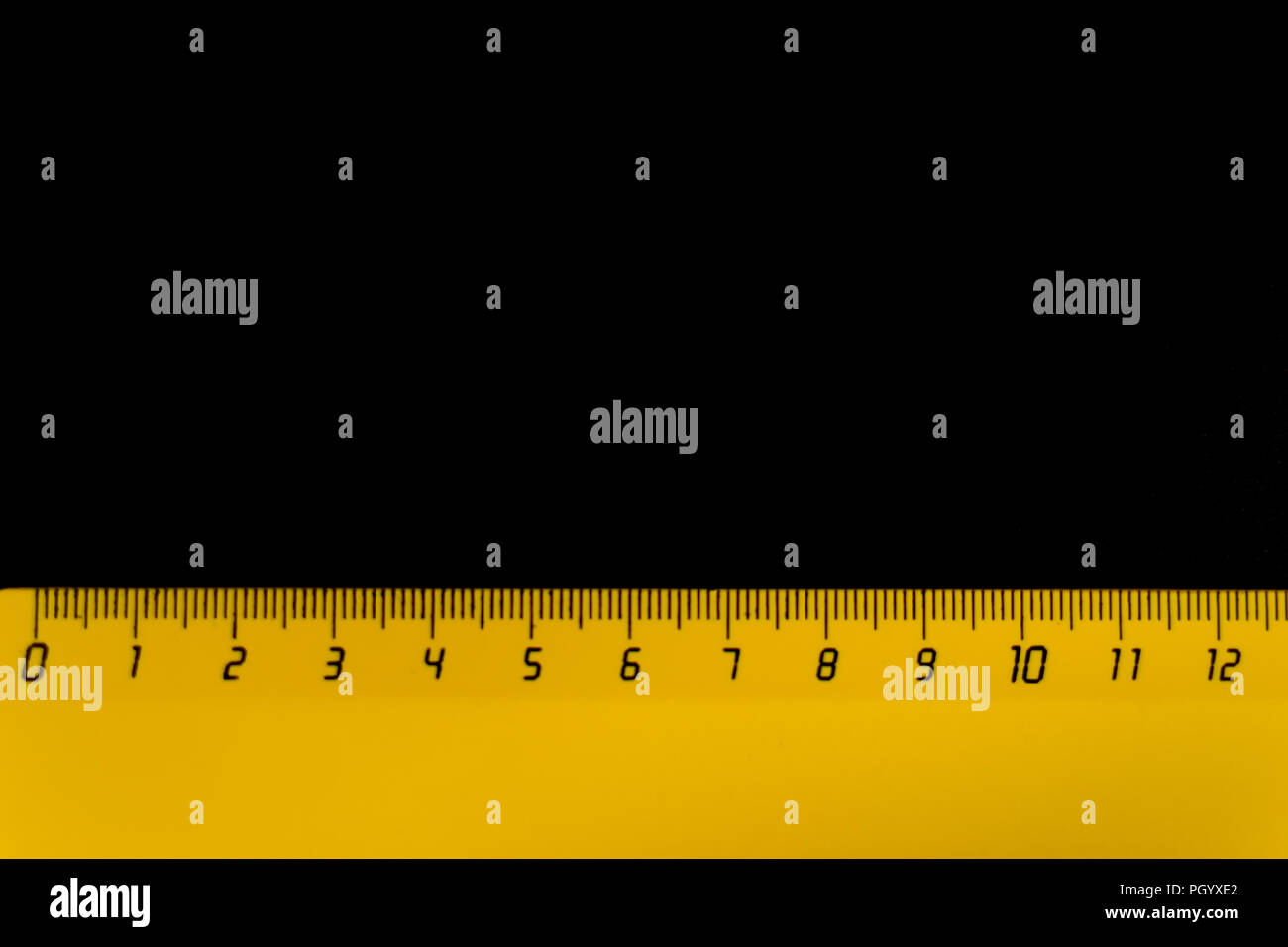 yellow ruler on a black background 12 centimeters Stock Photo