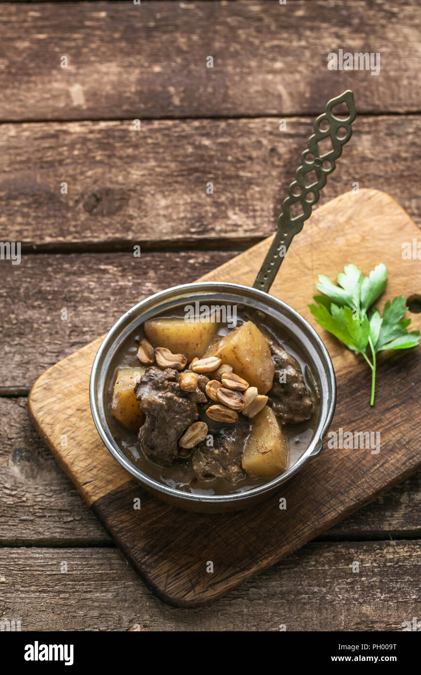 Portion of massaman curry in copper pan, top view, rustic style Stock Photo