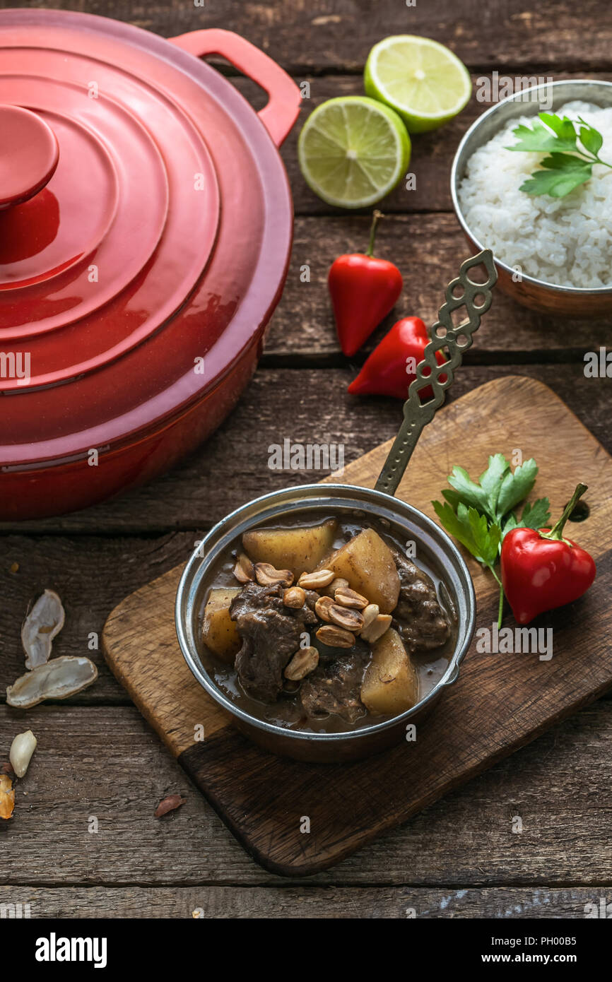 Massaman Beef Curry Served In copper pan, wooden background Stock Photo