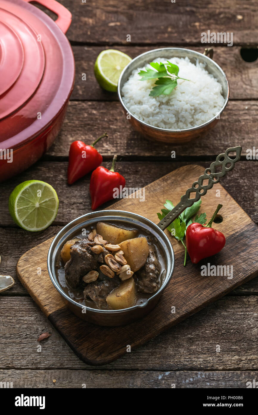 Massaman Beef Curry Served In copper pan, wooden background Stock Photo