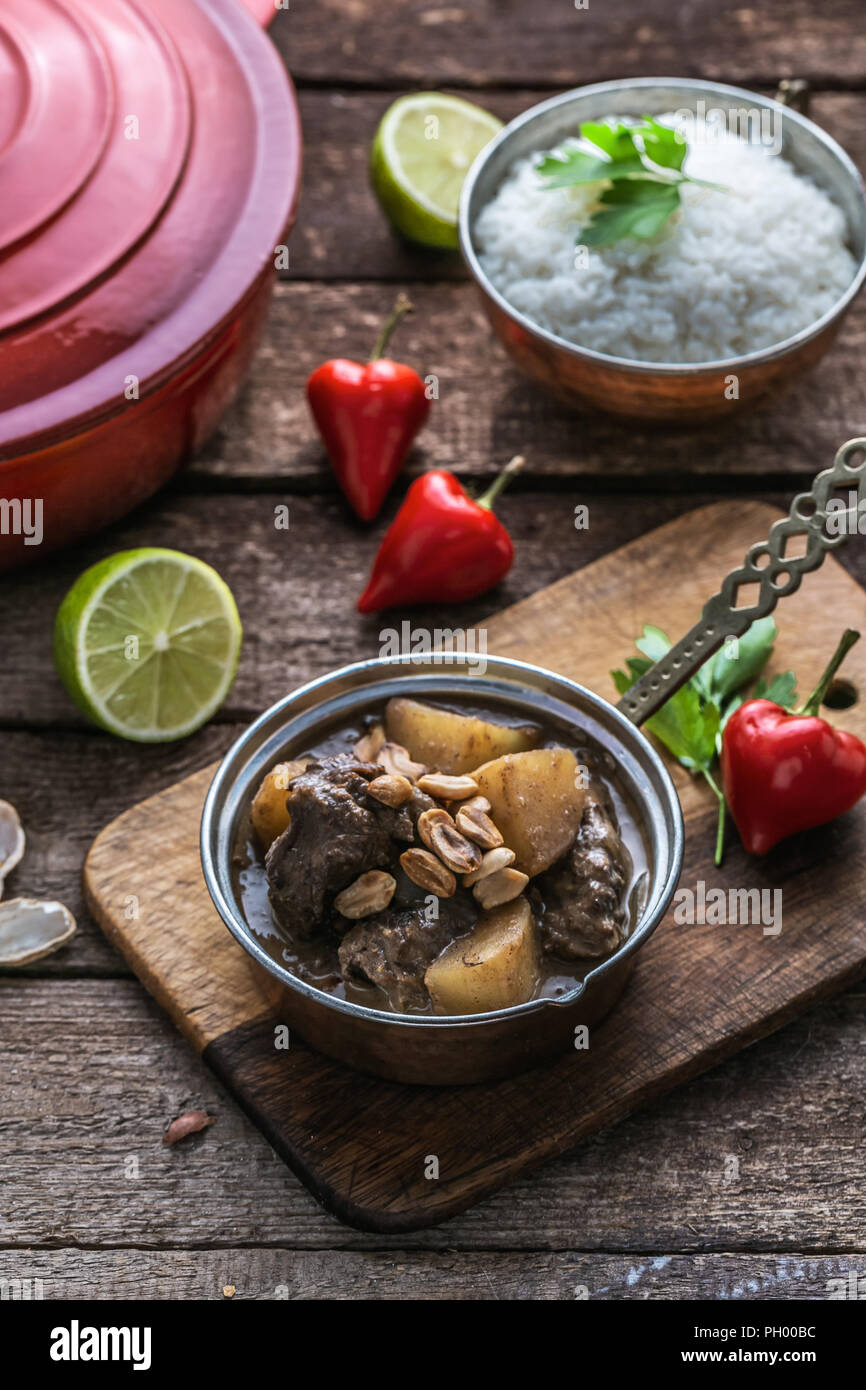 Massaman Beef Curry Served In copper pan, wooden background Stock Photo