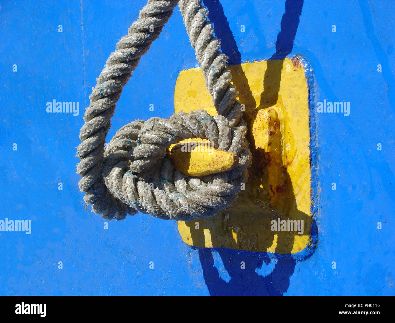 nautical rope tied around yellow cleat on bright blue ship Stock Photo ...