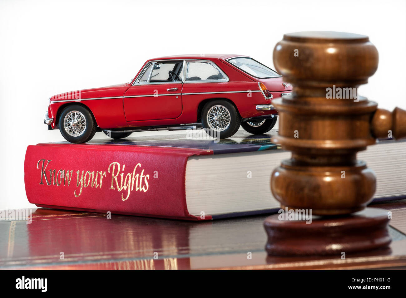 Auctioneers hammer in car saleroom auction buying selling situation with classic red MGB GT resting on legal advice reference book 'Know your Rights' Stock Photo
