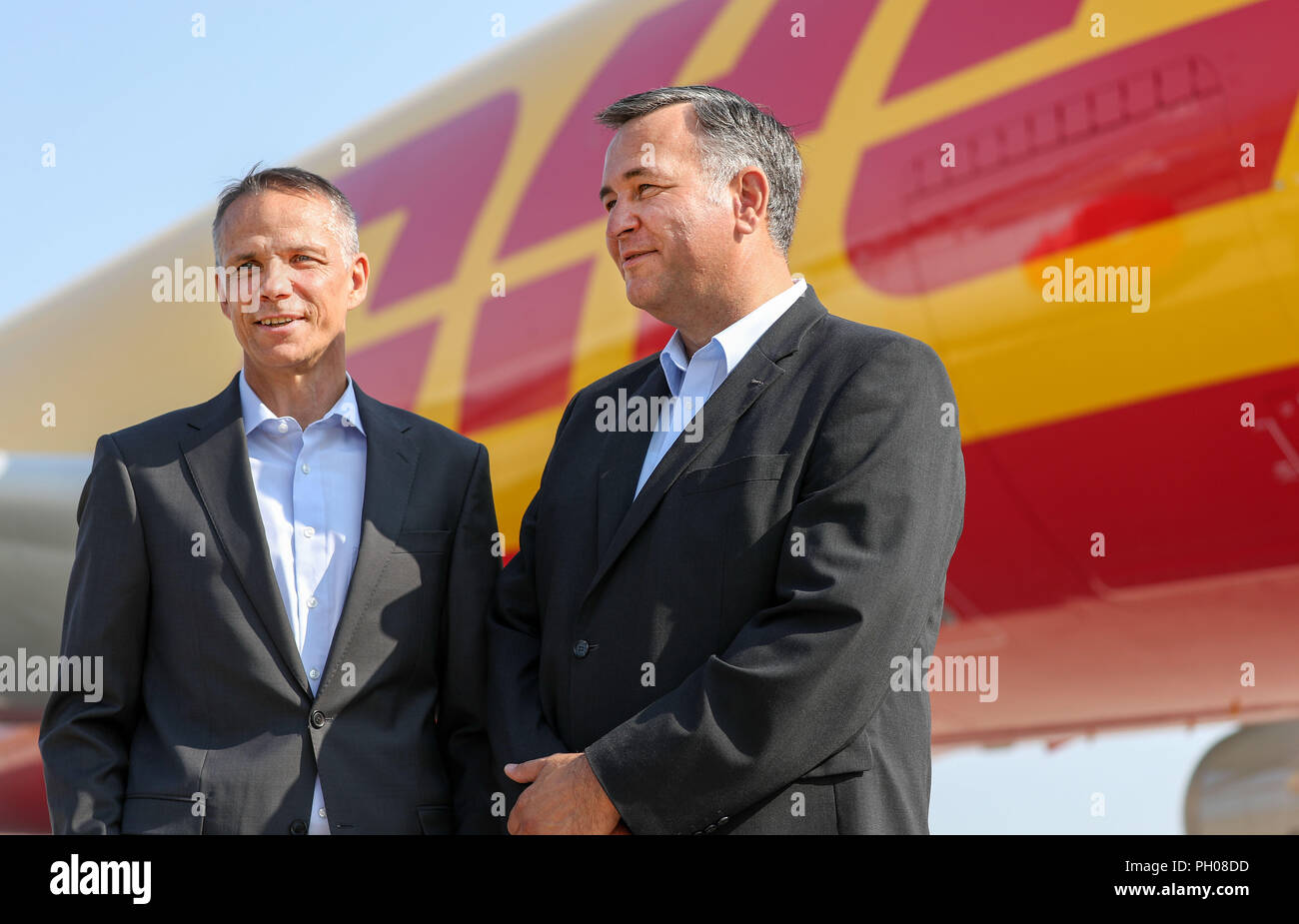 29 August 2018, Germany, Schkeuditz: Ralph Wondrak, CEO of DHL Hub Leipzig (l), and Markus Otto, CEO of European Air Transport Leipzig GmbH, are standing in front of a DHL freighter (Airbus A330 200) at Leipzig/Halle Airport. Ten years ago, the logistics company moved its hub from Brussels to Leipzig. Since then, the volume of air freight has been growing. Almost 1.14 million tons of freight were handled in 2017, an increase of 8.2 percent over the previous year. Up to 65 machines for DHL alone are in operation at the airport on working days. Photo: Jan Woitas/dpa-Zentralbild/dpa Stock Photo