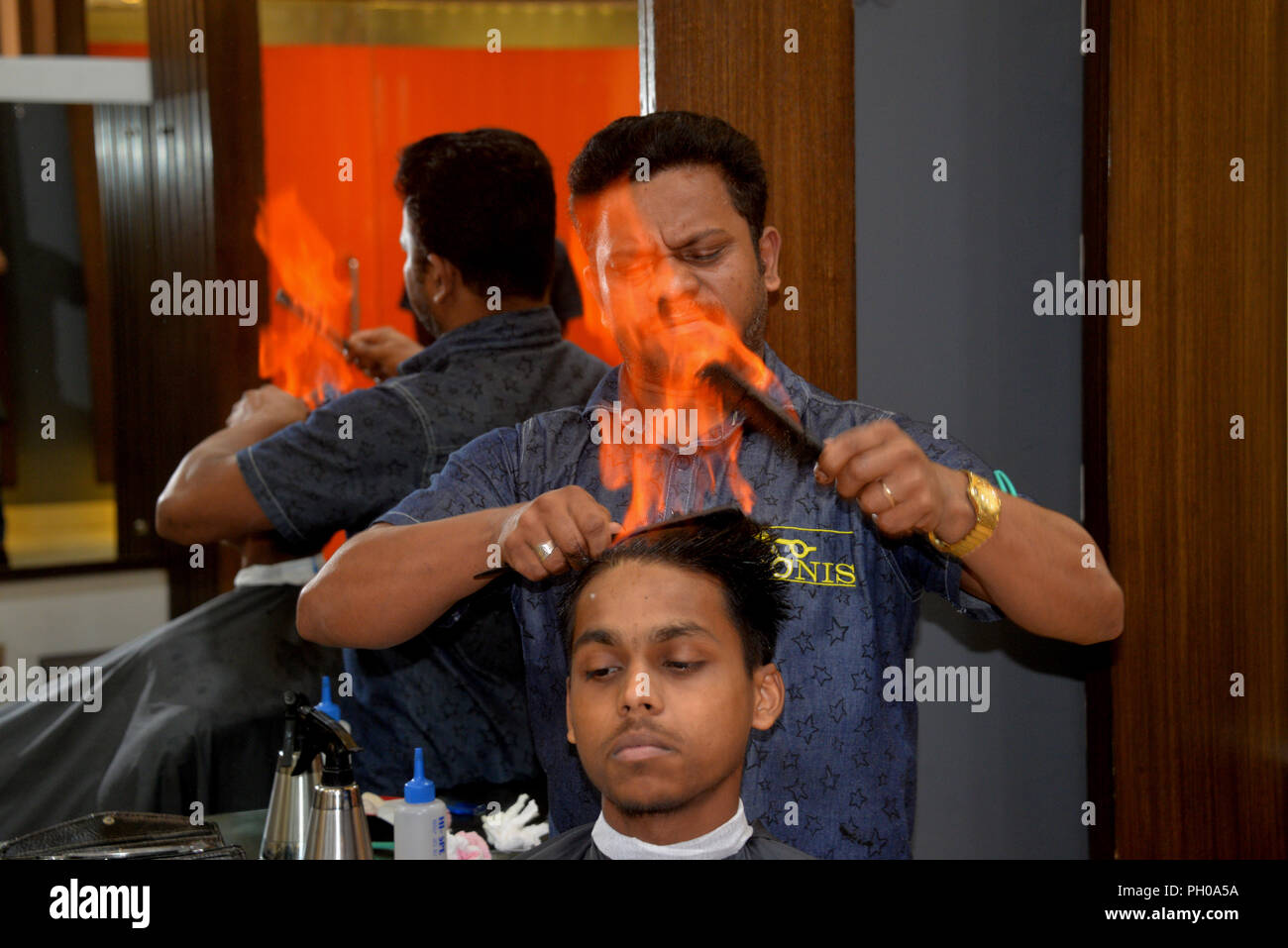 Dhaka, Bangladesh. 29th Aug, 2018. A barber uses fire to straighten a man's  hair at a salon in Dhaka, Bangladesh on Aug. 29, 2018. Hair burning is  becoming a new sensation for