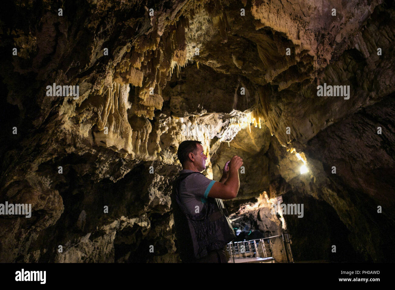 Hamedan, Iran. 27th Aug, 2018. A man takes pictures inside Alisadr cave in Hamedan province, western Iran, on Aug. 27, 2018. Alisadr Cave attracts thousands of tourists every year. Credit: Ahmad Halabisaz/Xinhua/Alamy Live News Stock Photo