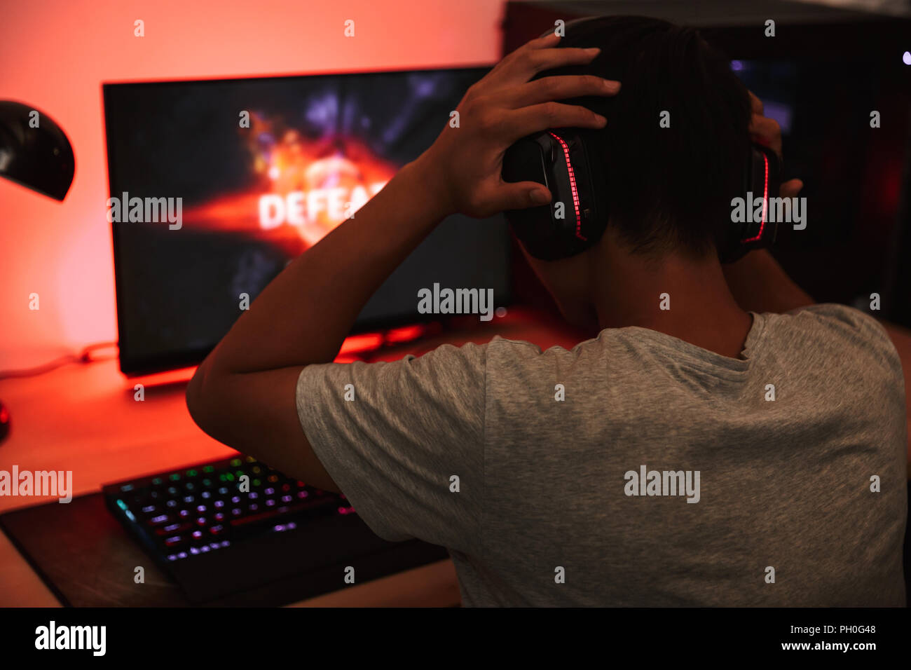 Portrait from back of teenage gamer boy playing video games on computer ...