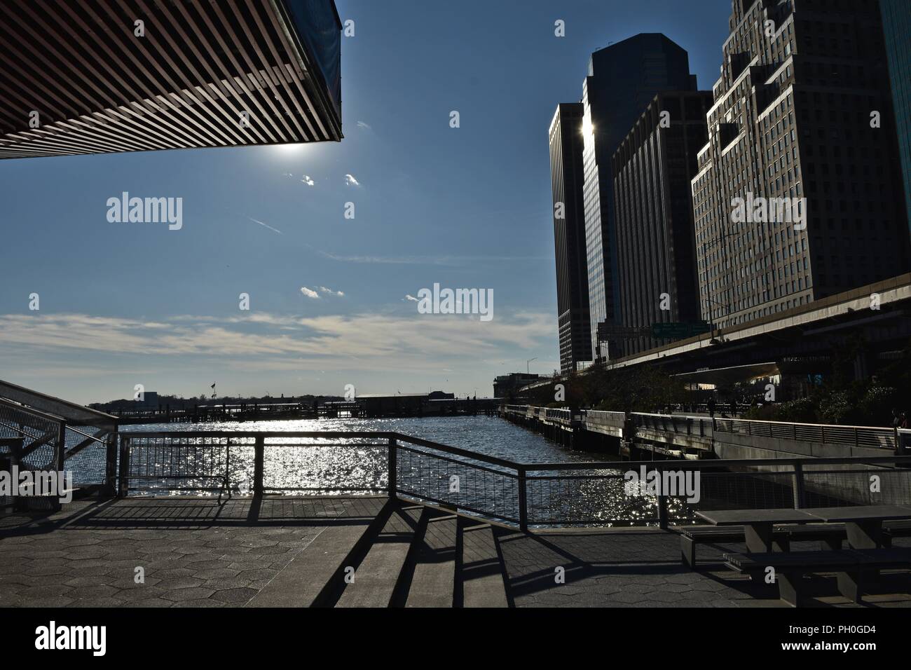 Manhattan cityscape as seen pier 15 against bright sun Stock Photo