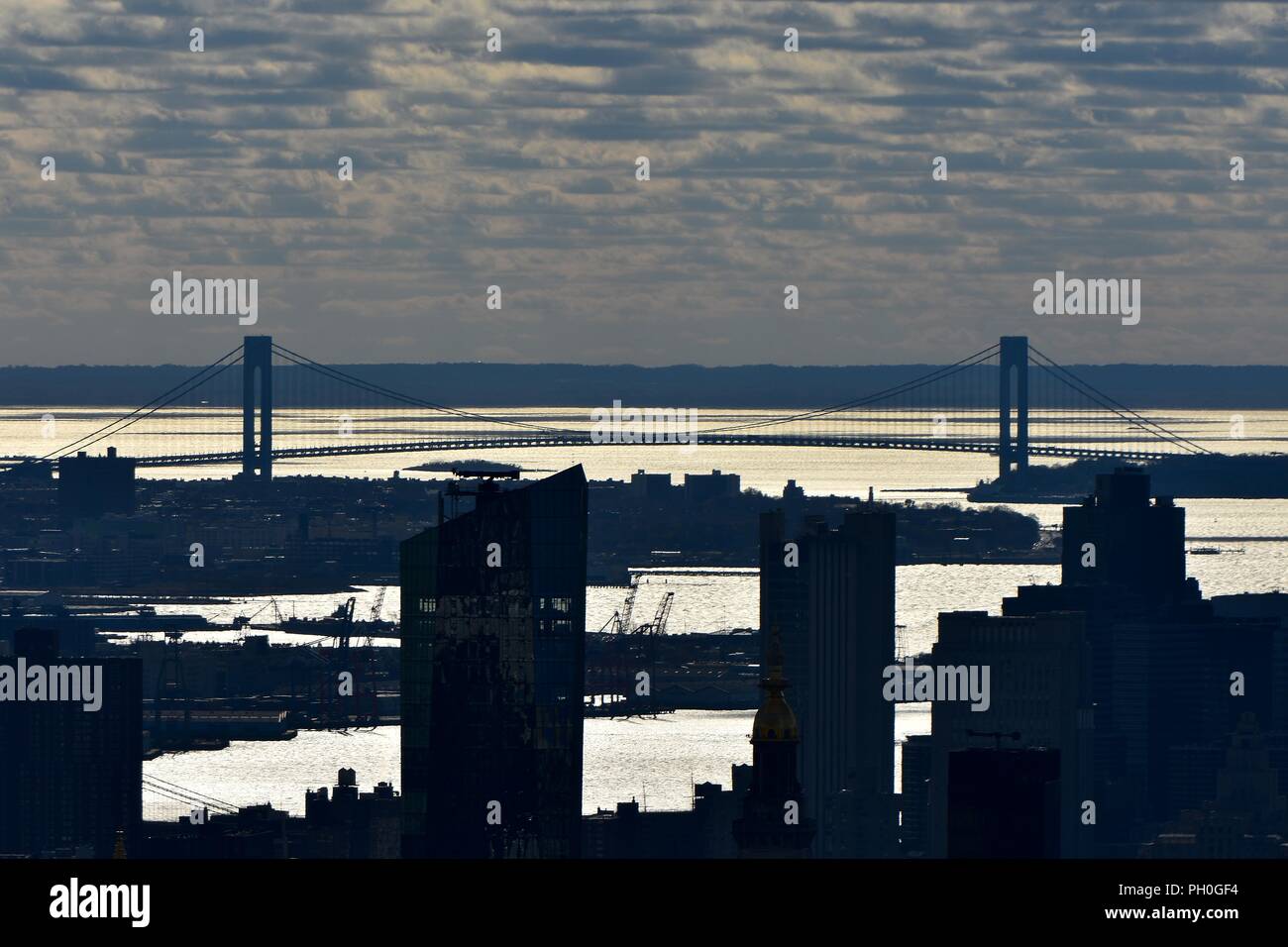 Silhouette of Verrazano-Narrows bridge shot at noon against bright sun reflection from water Stock Photo