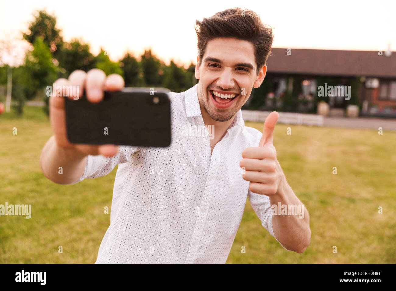 Picture of young happy man outdoors take a selfie by mobile phone with