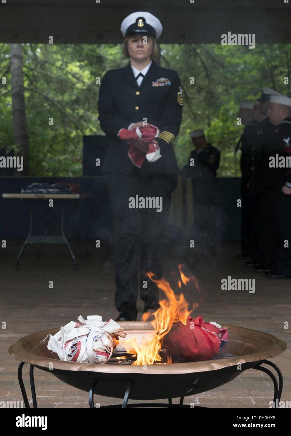BANGOR, Wash. (June 14, 2018) Chief Hospital Corpsman Farrah Ocasio, from Detroit, Michigan, assigned to Trident Training Facility in Bangor, Wash., walks the remains of a U.S. flag to a fire during a flag retirement ceremony at Naval Base Kitsap - Bangor. When a U.S. flag becomes worn, torn, faded, or badly soiled, the flag should be retired with the dignity and respect befitting it. The traditional method is to cut the flag into pieces, separating the 13 stripes from canton and incinerating them separately in a respectful manner. Stock Photo
