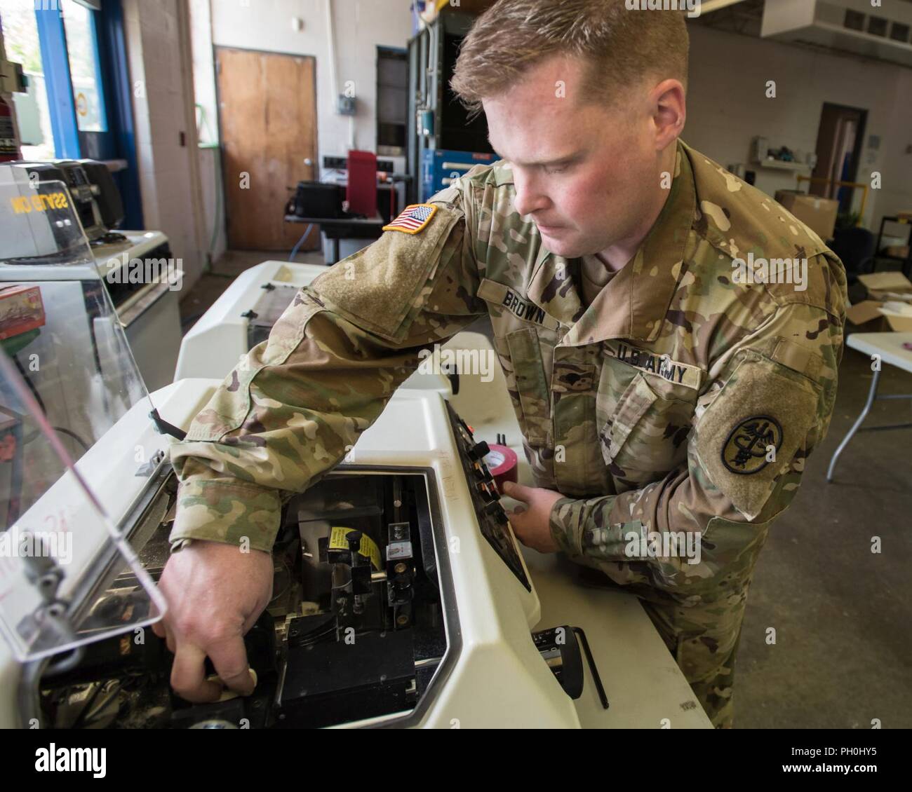 . Army Spc. Cameron Brown, an optical lab technician assigned to the  . Navy's Mobile Optical Support Unit at Naval Weapons Station Yorktown  (Pennsylvania), sets up equipment to make eyeglasses for a