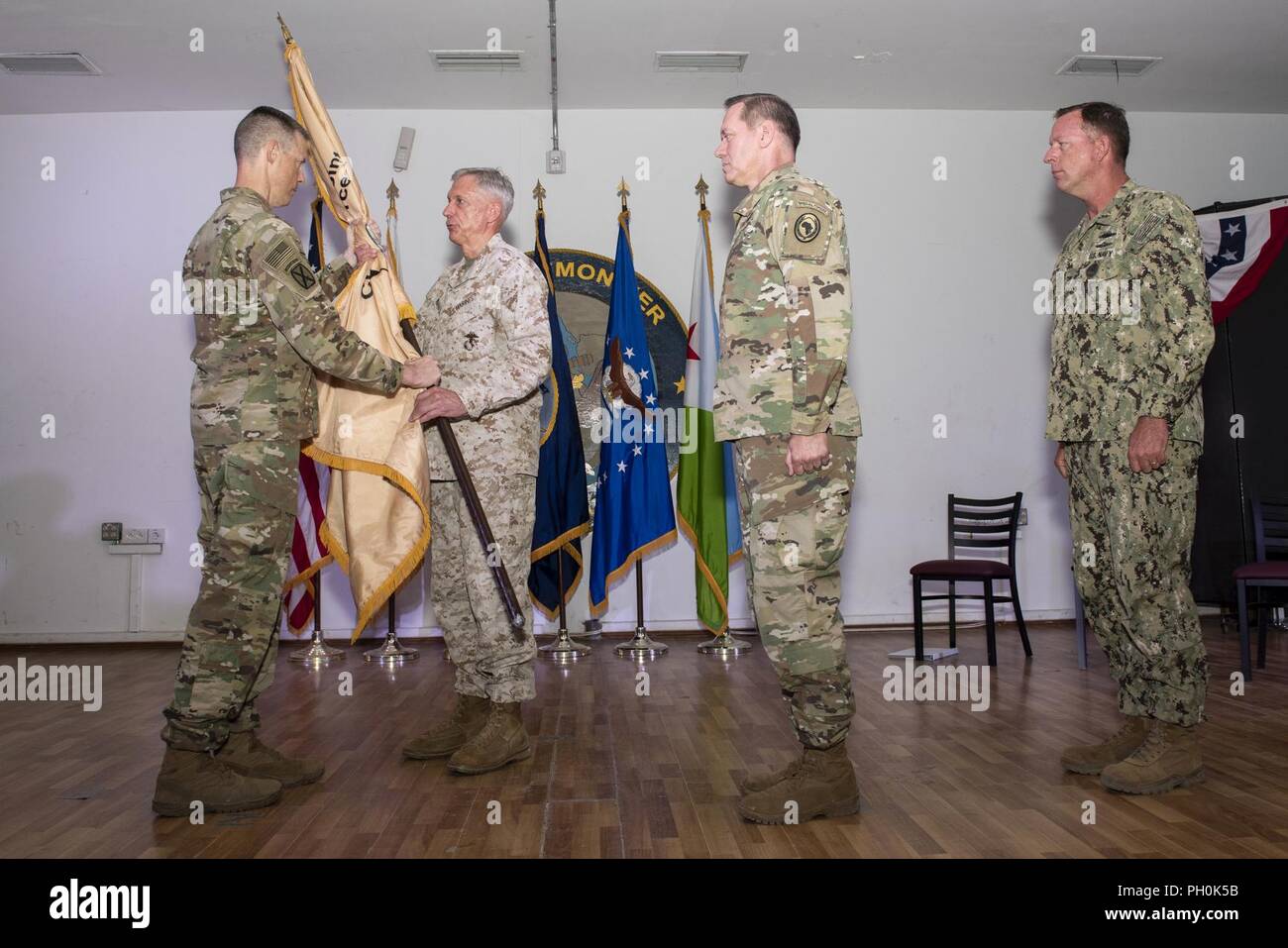 U.S. Army Brig. Gen. William Zana, outgoing commander, Combined Joint Task Force Horn of Africa, passes the task force flag to U.S. Marine Corps Gen. Thomas Waldhauser, commander of United States Africa Command, during a change of command ceremony on Camp Lemonnier, Djibouti, June 14, 2018. Zana will continue with the task force, resuming his previous position as deputy commander. Stock Photo