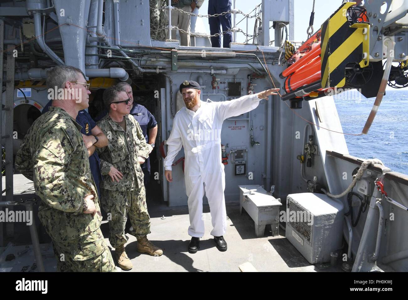 ARABIAN GULF (June 17, 2018) Lt. Tom Hasting, right, shows a Sea Fox inspection round to Vice Adm. Scott Stearney, commander of U.S. Naval Forces Central Command, U.S. 5th Fleet, Combined Maritime Forces, left, aboard HMS Middleton during Mine Countermeasures Exercise (MCMEX) 18-2. The bilateral exercise enhances cooperation, mutual MCM capabilities and interoperability between the U.S. and U.K., demonstrating the shared commitment of ensuring unfettered operations of naval and support vessels, as well as commercial shipping movements, throughout the maritime domain. Stock Photo