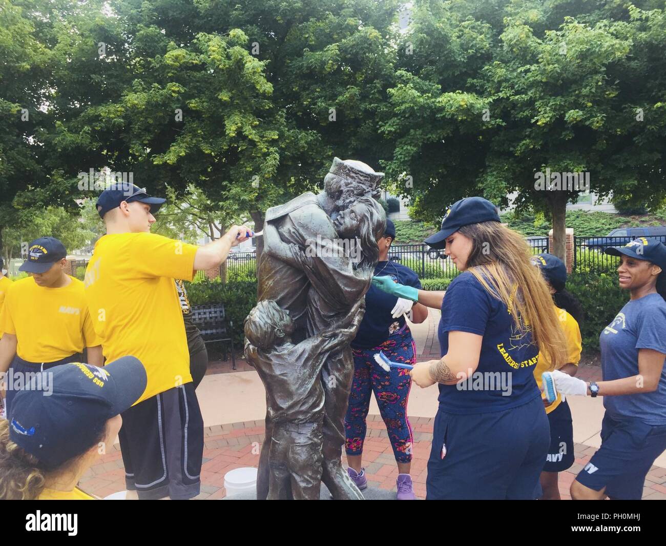 NORFOLK, Virginia (June 18, 2018) Sailors assigned to the aircraft carrier USS George H.W. Bush (CVN 77) clean the “Homecoming” statue at Norfolk’s Town Point Park. As a birthday tribute to the ship’s namesake, and representing his famous “Thousand Points of Light” speech, approximately 1,000 GHWB crew members took part in one of the largest single-day community relation (COMREL) events at 44 different locations throughout the Hampton Roads area. George H.W. Bush turned 94 on June 12. Stock Photo