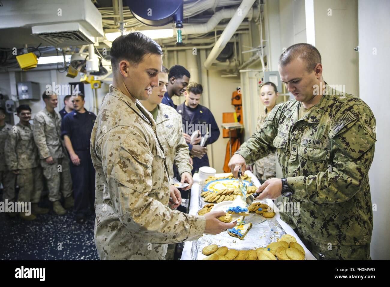 U.S. 5TH FLEET AREA OF OPERATIONS (June 17, 2018) U.S. Navy Corpsmen with the 26th Marine Expeditionary Unit (MEU), line up for a piece of cake after a ceremony celebrating the Navy Hospital Corps’ 120th birthday, aboard the Wasp-class amphibious assault ship USS Iwo Jima (LHD 7), June 17, 2018. The 26th MEU and Iwo Jima amphibious ready group are deployed to the U.S. 5th Fleet of operations in support of maritime security operations to reassure allies and partners and preserve the freedom of navigation and the free flow of commerce in the region. Stock Photo