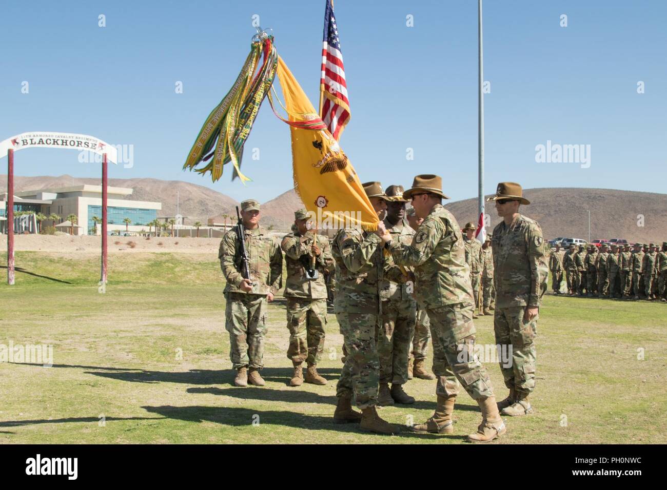 U.S. Army Col. Joseph Clark, commander, 11th Armored Cavalry Regiment, passes the 2nd Squadron, 11th ACR colors to incoming commander, Lt. Col. Russell Wagner, during the EAGLEHORSE change of command, on Fort Irwin’s Fritz Field, June 19, 2018. Stock Photo