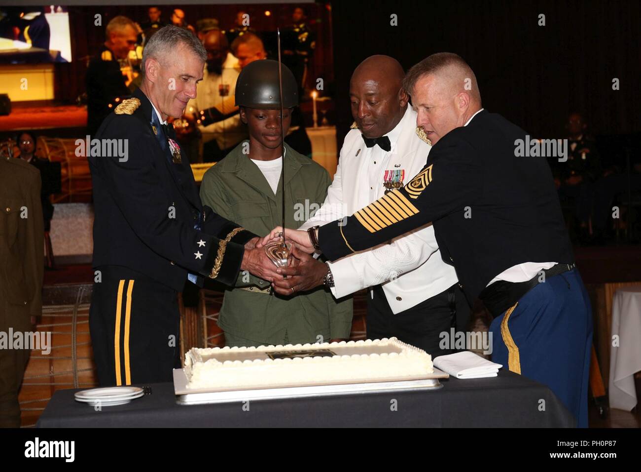 Pfc. Cynarra Strickland, assigned to 35th Combat Sustainment Support Battalion, participates in the cake-cutting ceremony during the ball for 243rd Army Birthday held at Camp Zama Community Club June 14, 2018 along with Maj. Gen. James F. Pasquarette, left, commanding general of U.S. Army Japan, and Command Sgt. Maj. Richard Clark, right, command sergeant major of USARJ. Stock Photo