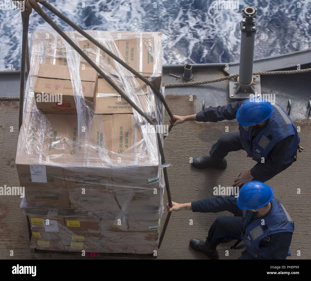 MEDITERRANEAN SEA (June 14, 2018) Seaman Trenton Heil, bottom, from Ennis, Texas, and Boatswain’s Mate Seaman John Baltuskonis, from Waldwood, New Jersey, receive cargo at the replenishment station aboard the San Antonio-class amphibious transport dock ship USS New York (LPD 21) during a replenishment-at-sea June 14, 2018. New York, homeported in Mayport, Florida, is conducting naval operations in the U.S. 6th Fleet area of operations in support of U.S. national security interests in Europe and Africa. Stock Photo