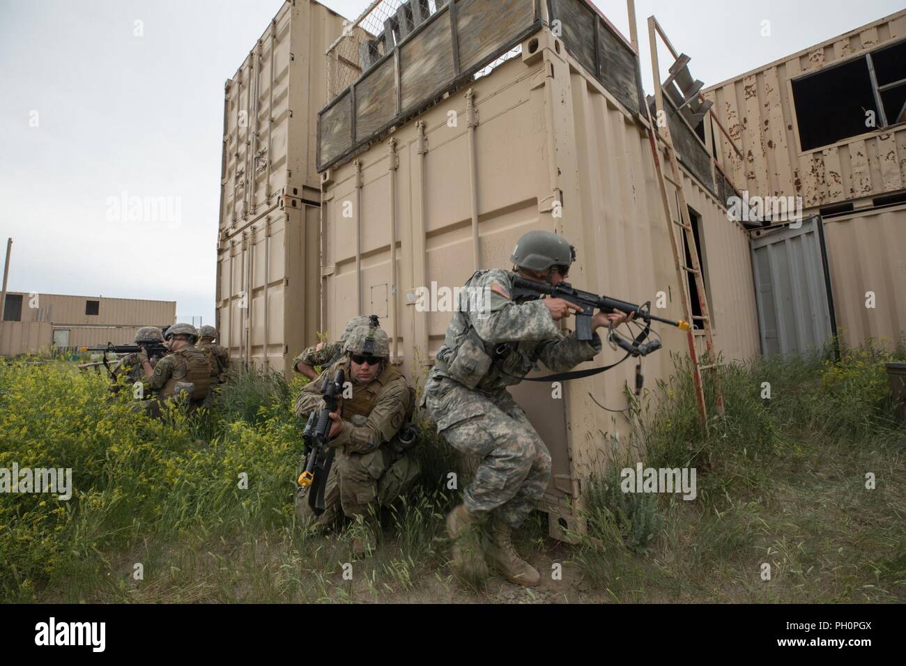 U.S. Soldiers with the 211th Engineer Company (Mobility and Augmentation Company) of the South Dakota Army National Guard breach a door after detonating an explosive charge to assault a mock village in the North Training Area of Camp Guernsey, WY, on June 16, 2018. The Golden Coyote training exercise is a three-phase, scenario-driven exercise conducted in the Black Hills of South Dakota and Wyoming, which enables commanders to focus on mission essential task requirements, warrior tasks and battle drills. Stock Photo