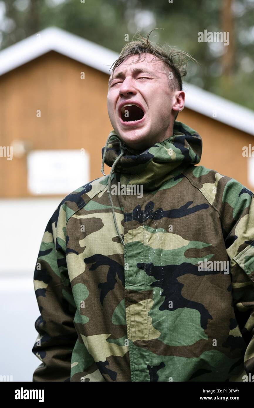 U.S. Army Spc. Derek Teegardin with 1st Battalion, 4th Infantry Regiment, Joint Multinational Readiness Center, 7th Army Training Command (7ATC), feels the effect after exiting the gas chamber during the chemical, biological, radiological and nuclear lane as part of the 7ATC Best Warrior Competition June 20, 2018 at Grafenwoehr Training Area, Germany. Teegardin, a Battle Creek, MI native is competing in the three-day event ending June 21 with the announcement of the 7ATC Officer, Noncommissioned Officer and Soldier of the Year. The winners will move on to compete in the U.S. Army Europe Best W Stock Photo