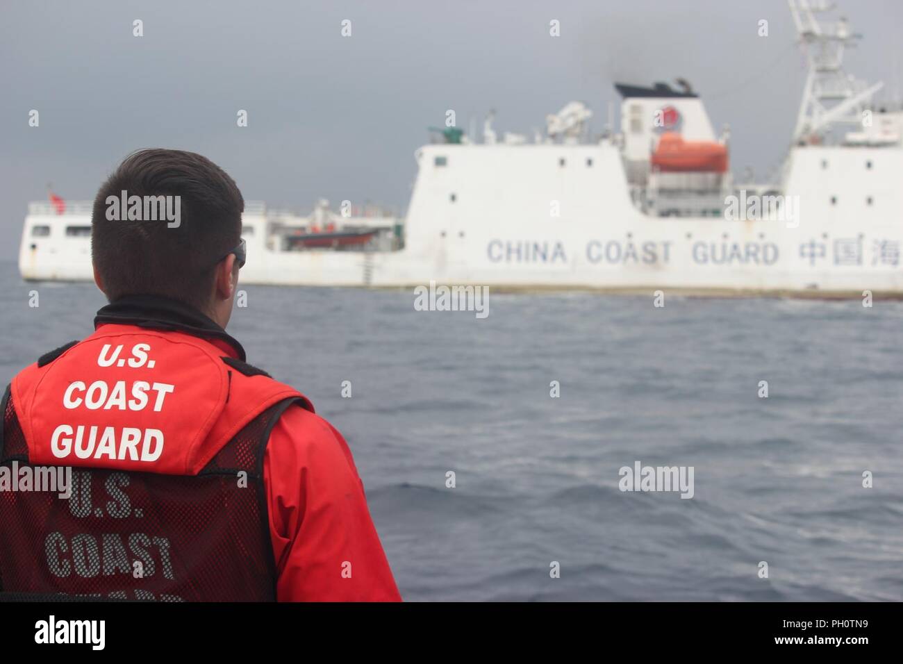 A crew member of the USCGC Alex Haley (WMEC 39) stands lookout during a transfer of custody of the detained fishing vessel Run Da with the People's Republic of China Coast Guard in the Sea of Japan, June 21, 2018. The Alex Haley and PRC Coast Guard crews detained the Run Da suspected of illegal high seas drift net fishing. Stock Photo