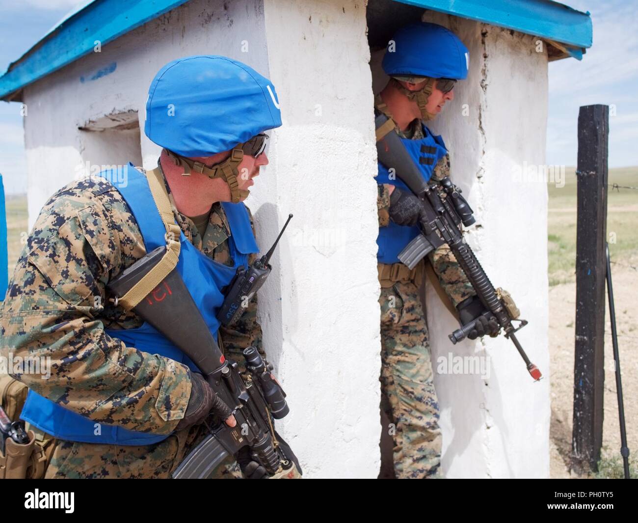 U.S. Marine Corps Cpl. Domenick DiGiovannangelo, and Lance Cpl. Tanner Yeager, both of 3rd Law Enforcement Battalion, take cover after two men initiated a simulated firefight June 20, 2018, during Khaan Quest 2018 entry control point operations training at Five Hills Area, Mongolia. The purpose of Khaan Quest is to gain U.N. training and certification for the participants through the conduct of realistic peace support operations, to include increasing and improving U.N. peacekeeping interoperability and military relationships among the participating nations. Stock Photo