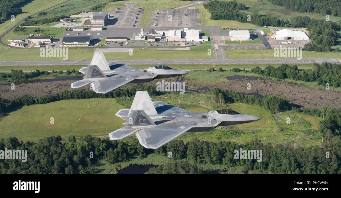 Two U.S. Air Force F-22 Raptors fly over Joint Base Langley-Eustis’ Felker Army Airfield at Fort Eustis, Virginia, June 14, 2018. Felker Army Airfield represents the success of consolidating Army and Air Force operations through a joint base as the airfield continues to support aerial missions while being operated by the Air Force’s 1st Operations Support Squadron. Stock Photo
