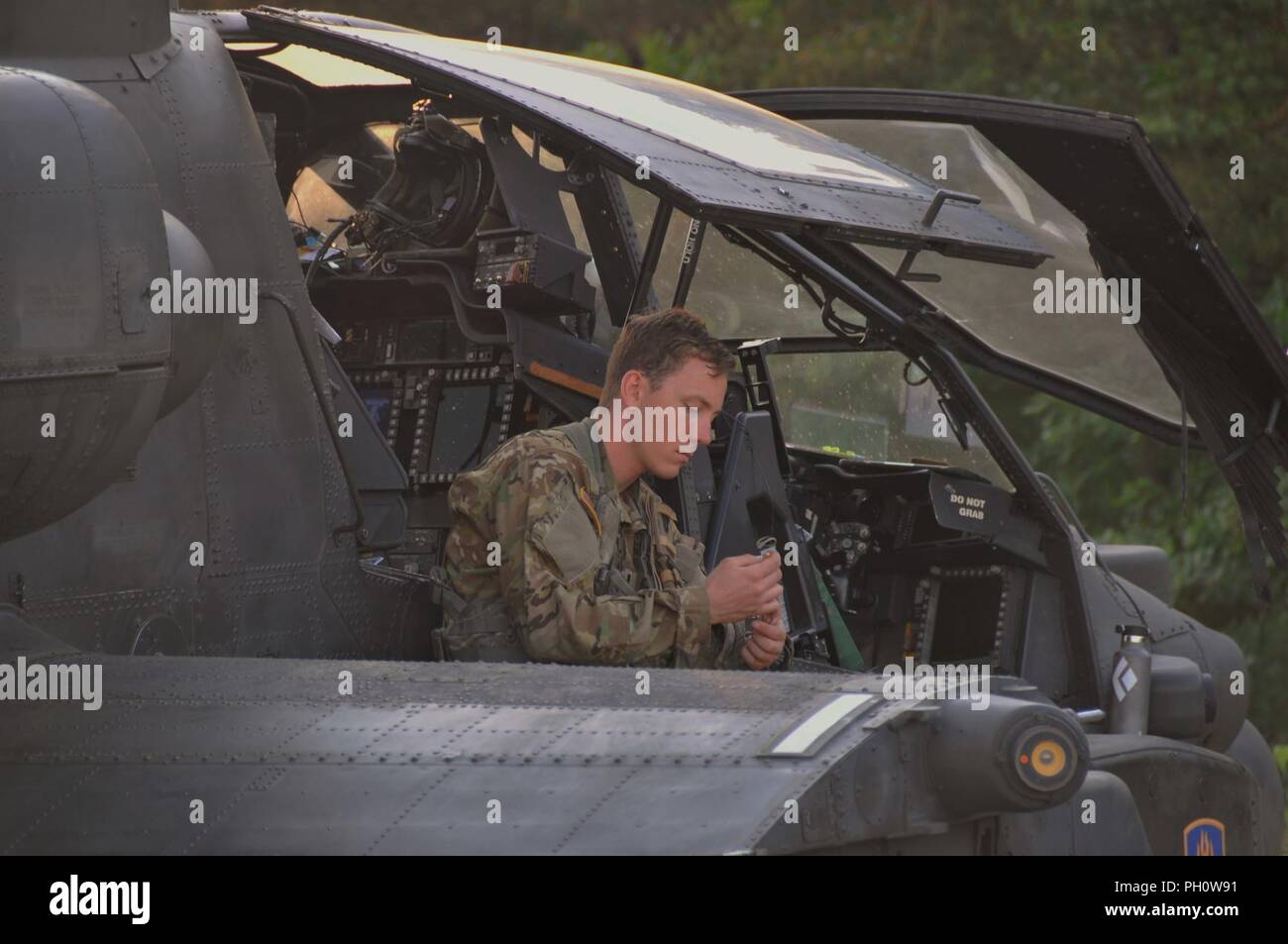 A U.S. Army Apache helicopter pilot assigned to Task Force Viper 1st Battalion, 3rd Aviation Regiment, 12th Combat Aviation Brigade makes final checks before departing Zagan Poland Training Area on June 21, 2018. Stock Photo