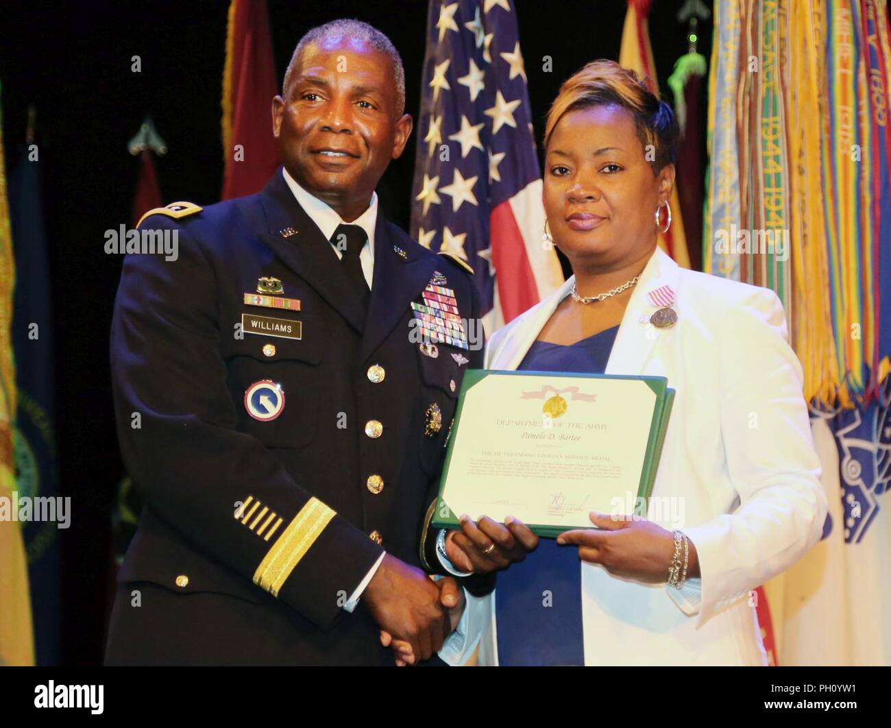 Lt. Gen. Darrell K. Williams, director of the Defense Logistics Agency, Fort Belvoir, presents Pamela Bartee, wife of Command Sgt. Maj. Nathaniel J. Bartee Sr., with the Outstanding Civilian Service  certificate during the retirement ceremony for her husband June 20 at the Lee Theater. Stock Photo