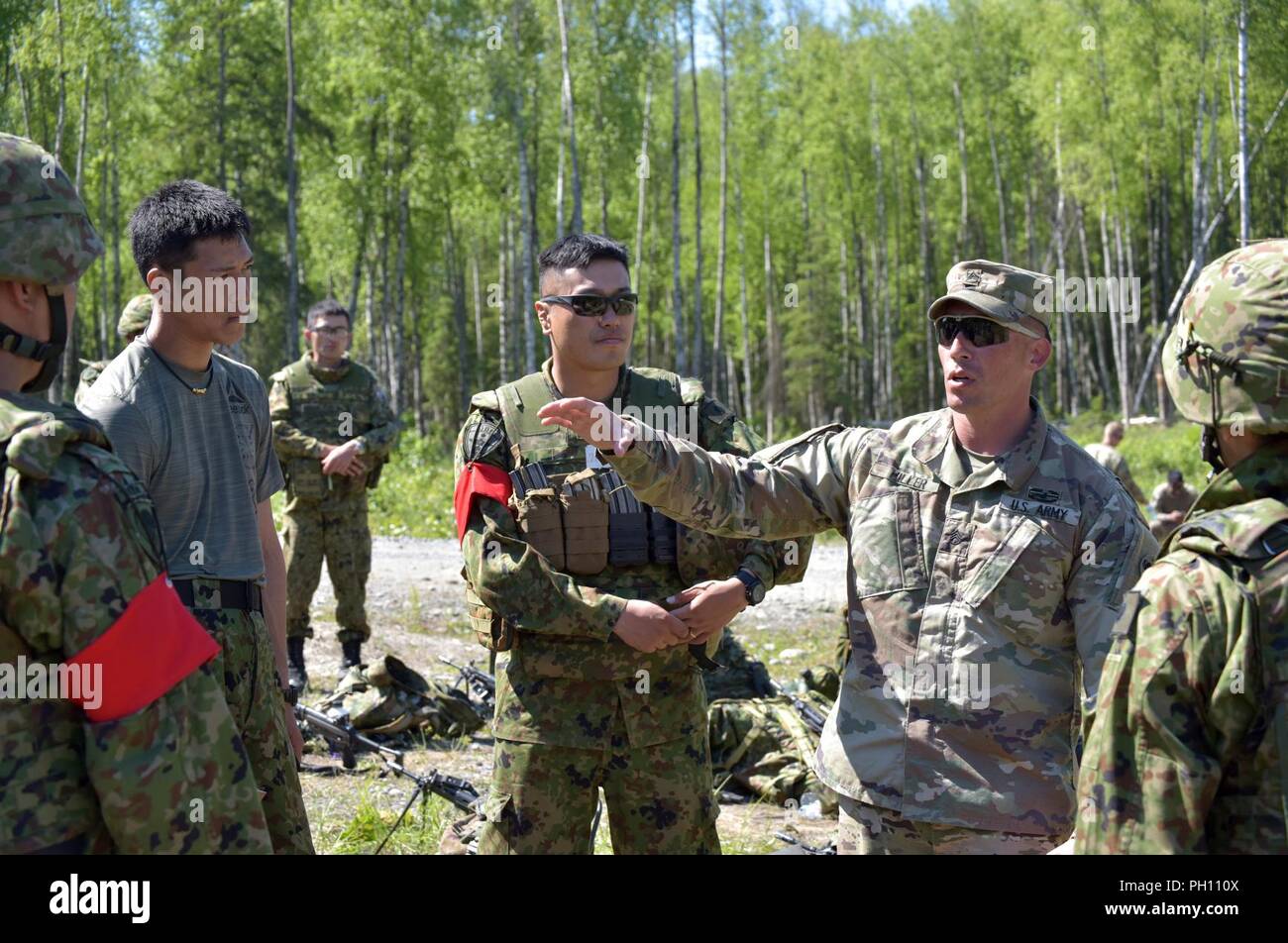 Staff Sgt. Lucas Miller, from U.S. Army Alaska’s 17th Combat Sustainment Support Battalion, discusses elements of training with 1st Airborne Brigade Japanese Ground Self-Defense Force paratroopers at Joint Base Elmendorf-Richardson as part of exercise Arctic Aurora, June 14, 2018. Miller acted as an interpreter during the exercise, a yearly bilateral training exercise involving elements of U.S. Army Alaska and the JGSDF, which focuses on strengthening ties between the two by executing combined small unit airborne proficiency operations and basic small arms marksmanship with a focus on combat r Stock Photo
