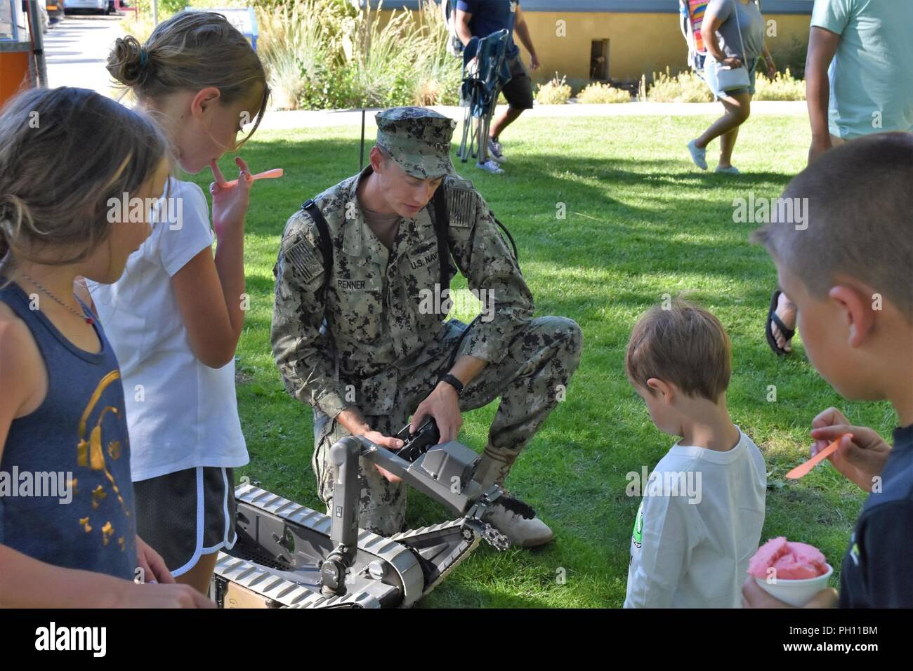 RENO, Nev. (June 20, 2018) Navy Diver 2nd Class Adam Renner from Southwest Regional Maintenance Center in San Diego, demonstrates an explosive ordinance disposal robot to children at Reno's Feed the Camel festival.  Renner, of Hershey, Pa., was one of many Sailors in town for Navy Week. Navy Week programs serve as the U.S. Navy's principal outreach effort into areas of the country that lack a significant Navy presence, helping Americans understand that their Navy is deployed around the world, around the clock, ready to defend America at all times. Stock Photo