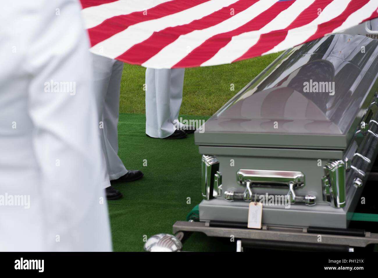 NORMANDY, France (June 19, 2018) The U.S. Naval Hospital Naples honor guard holds the American flag over the remains of Radioman 2nd Class Julius “Henry” Pieper during his funeral service at Normandy American Cemetery. Henry Pieper and his twin brother, Radioman 2nd Class Ludwig “Louie” Pieper, were both killed when their ship, Landing Ship Tank (LST) 523, struck an underwater mine off the coast of France on June 19, 1944. Louie’s remains were found immediately, but Henry’s remains weren’t identified until December 2017. The family requested that Henry be buried in Normandy next to his brother Stock Photo
