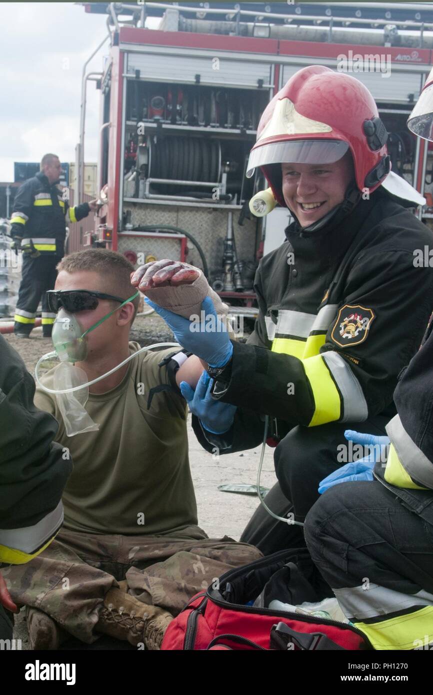 U.S. Army Spc. Dakotajames Osborne, an ammunition specialist assigned to the 962nd Ordnance Company, 143rd Combat Sustainment Support Battalion, receives medical aid from a Polish fire fighter during a joint military, civilian emergency responder training exercise in Swieteszow, Poland, June 20, 2018. The 962nd Ordnance, a U.S. Army Reserve unit from New York, is deployed in support of Atlantic Resolve in Europe. Stock Photo