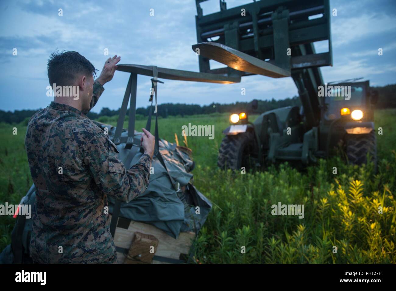 U.S. Marine Corps Staff Sgt. William Ressler, with Landing Support Company, 2nd Transportation Battalion, 2nd Marine Logistics Group, load a joint precision air delivery system onto an extendable boom forklift truck on Camp Lejeune, N.C., June 21, 2018. LS Company assessed the capabilities and limitations of the joint precision air delivery system, a global positioning satellite enhanced autonomous air resupply package, in an effort to automate and modernize the Marine Corps. Stock Photo