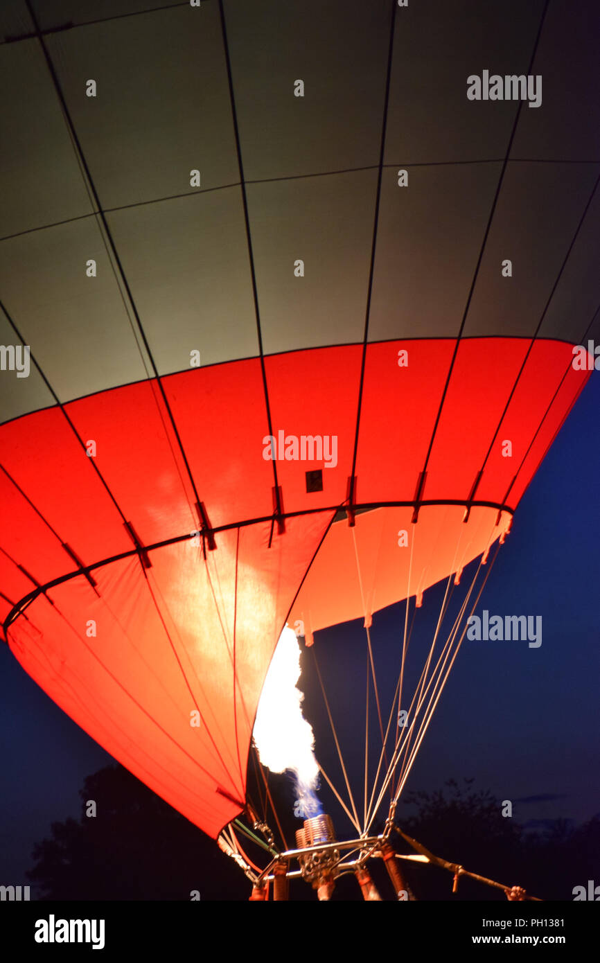 bright shining hot air balloon by night, burner with a extreme hot flame light up the inside of a red yellow hot air balloon Stock Photo
