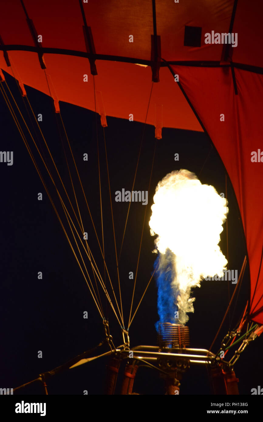 hot air balloon with burner by night, burner with a extreme hot flame light up the inside of a red hot air balloon Stock Photo
